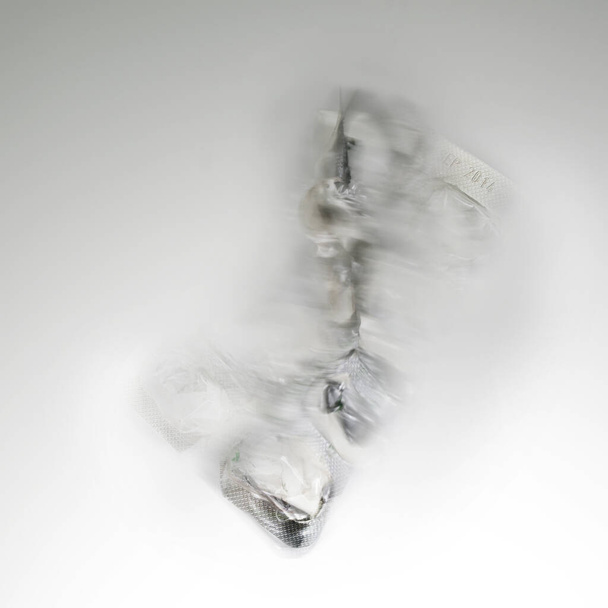Abstract motion blur of a blister packaging for pills made from aluminum and plastic on a light gray background, concept for healthcare and drug addiction, also for cast away waste, microplastic and environmental protection, copy space - Photo, Image