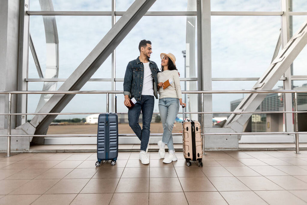 Ταξίδι του μέλιτος. Ρομαντικό νεαρό αραβικό ζευγάρι στέκεται με βαλίτσες στο αεροδρόμιο - Φωτογραφία, εικόνα