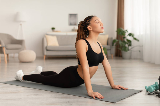 Afro-Amerikaanse vrouw doet yoga oefening om terug Indoor te versterken - Foto, afbeelding