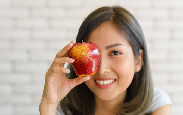 Retrato de una hermosa mujer asiática sonriente sosteniendo manzana roja. de cerca - Foto, Imagen