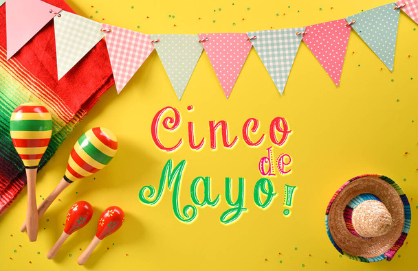 マラカス、メキシコのブランケットストライプやポンチョのセレープと黄色の背景にテキストと帽子から作られたシンコ・デ・マヨの休日の背景. - 写真・画像