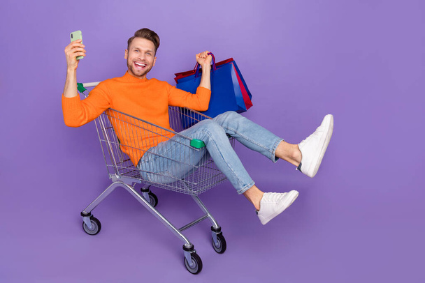 Full body photo of good mood excited man go shopping during black friday sale discount isolated on purple color background - Photo, image