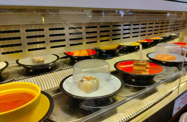 Close up view of running sushi trail with a lot of small dishes running back and forth. - Photo, Image