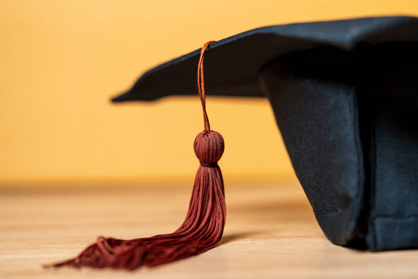 Black Graduation Hat placed on wood desk background - 写真・画像