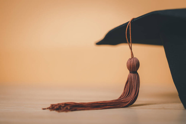 Black Graduation Hat auf Holz Schreibtisch Hintergrund platziert - Foto, Bild
