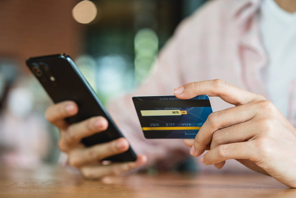 Mains tenant la carte de crédit en utilisant le téléphone intelligent Achats en ligne et concept de paiement - Photo, image