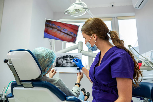 in professional dentistry, a dentist who knows his business takes pictures for a patient with diseased teeth. The concept of pictures of teeth in patients - Valokuva, kuva