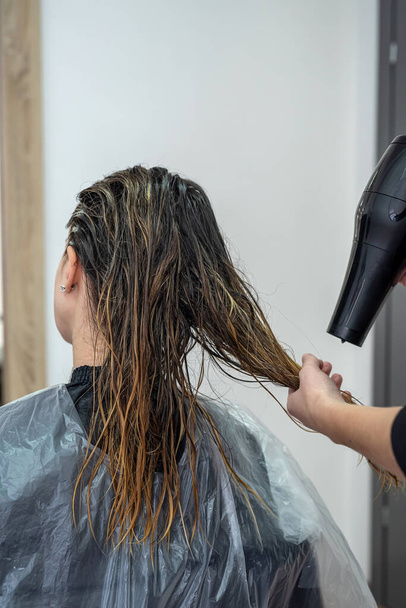 a beautiful girl who came to the beauty salon for the first time did bleaching and drying her hair to apply paint. Hair drying concept. Beauty salon concept - Photo, Image