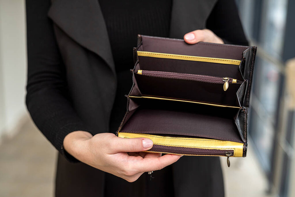 stylish lady in a black classic suit holds an open empty wallet in her gentle hands. Empty wallet concept - Fotografie, Obrázek