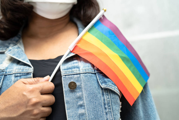 LGBT gurur ayının sembolü Asyalı kadın elinde gökkuşağı bayrağı, Haziran ayının geleneksel gay, lezbiyen, biseksüel, transseksüel, insan haklarını kutluyor. - Fotoğraf, Görsel