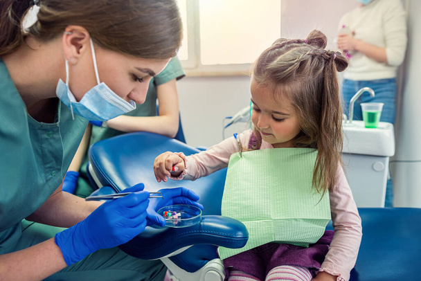 joven dentista mujer cepillarse los dientes para niña niña. El concepto de cepillarse los dientes en un niño - Foto, imagen