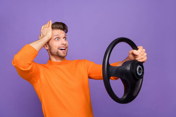 Photo of impressed shocked guy wear orange sweater driving car arm head looking empty space isolated violet color background - Foto, Imagem