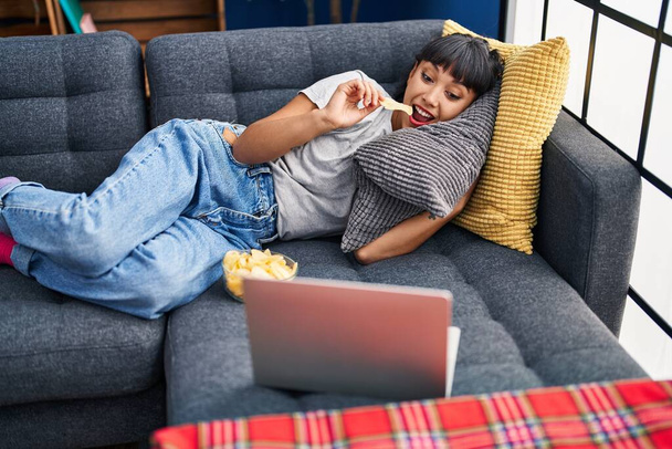Молодая женщина смотрит кино, лежащее дома на диване - Фото, изображение