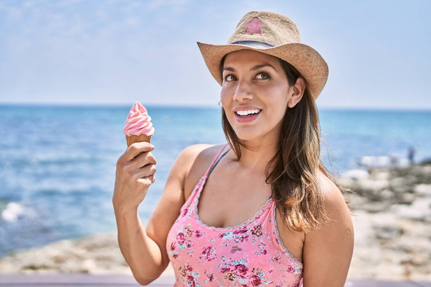 Брюнетка наслаждается летним днем на пляже, поедая мороженое - Фото, изображение