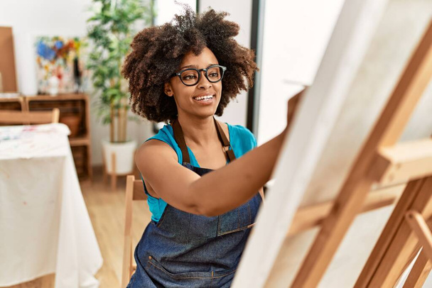 Joven mujer afroamericana sonriendo dibujo confiado en el estudio de arte - Foto, Imagen