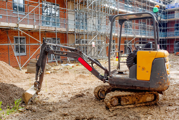 Construction works in progress on new residential building site and mini digger in front of it - Photo, Image