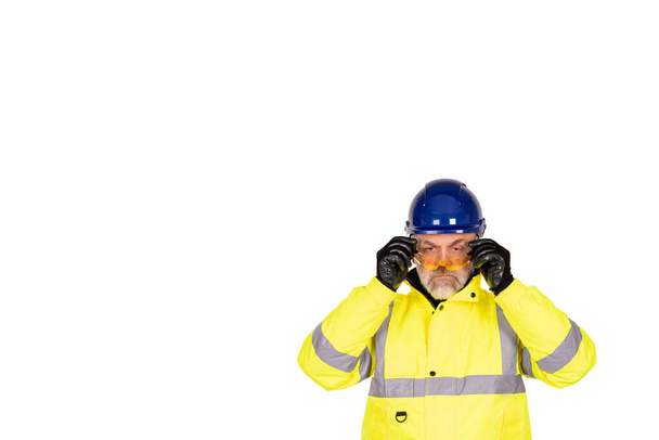 Un ouvrier de la construction vêtu d'un manteau hi-viz jaune vif et de gants de sécurité portant des lunettes de sécurité teintées pour une protection oculaire isolée sur fond blanc. Concept de bannière de sécurité sur chantier - Photo, image