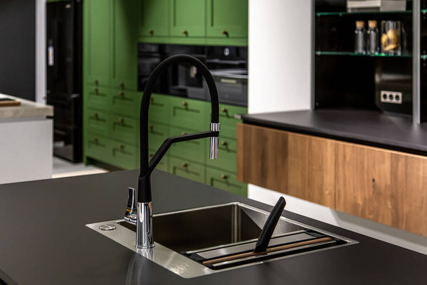 Modern bir mutfakta çelik lavabosu olan siyah bir musluk. Yenilenmiş dairede minimalizm. - Fotoğraf, Görsel