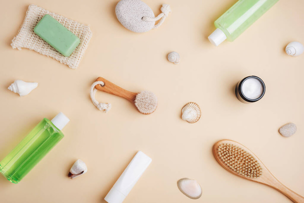Cosmetic flat lay on neutral beige background. Shower gel, bath foam, body brush, face cream, natural soap, pumice stone and body lotion. Spa and wellness concept. Top view - Foto, Imagen