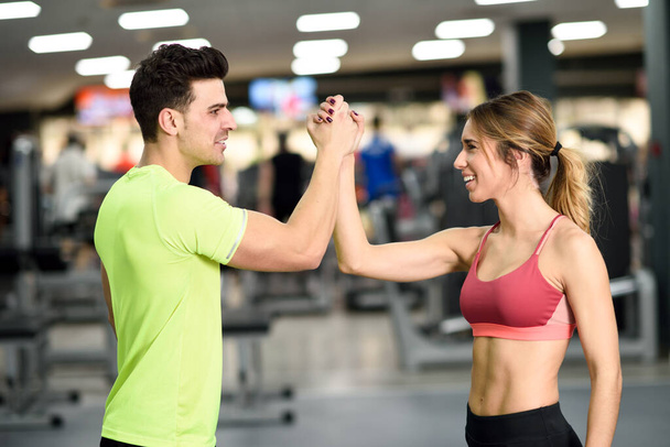 Lächelnder junger Mann und Frau macht High Five im Fitnessstudio - Foto, Bild