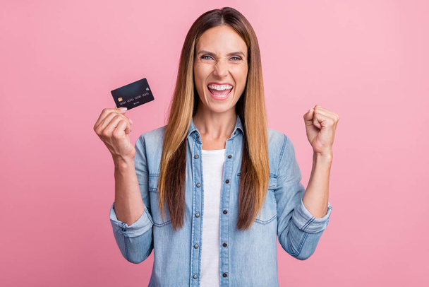 Photo of young excited woman celebrate success luck profit income bank card isolated over pink color background - Foto, Imagen