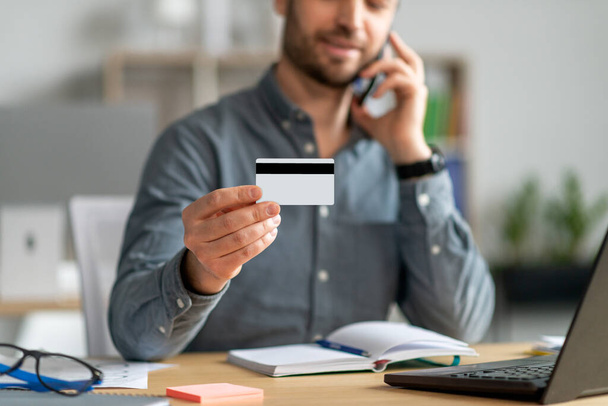 Kredi kartı tutan, müşteri hizmetleri temsilcisiyle telefon görüşmesi yapan tanınmamış yetişkin bir işadamı. - Fotoğraf, Görsel