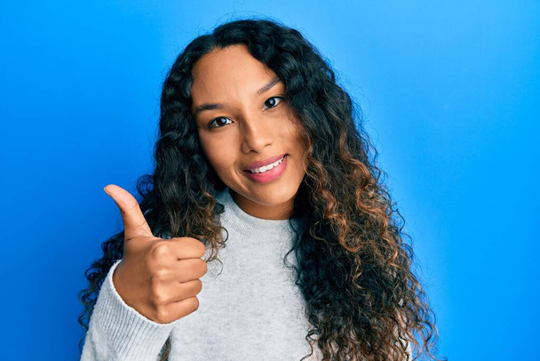 Young latin woman wearing casual clothes doing happy thumbs up gesture with hand. approving expression looking at the camera showing success.  - Photo, Image