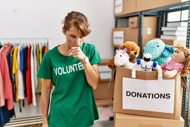 Beautiful caucasian woman wearing volunteer t shirt at donations stand feeling unwell and coughing as symptom for cold or bronchitis. health care concept.  - Photo, Image