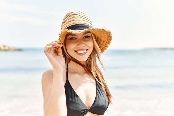 Jovem cuacasian menina sorrindo feliz vestindo biquíni de pé na praia. - Foto, Imagem