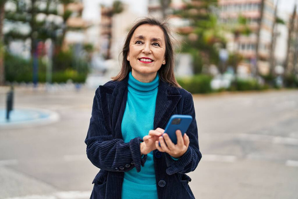 Mujer de mediana edad ejecutivo de negocios utilizando el teléfono inteligente en la calle - Foto, Imagen