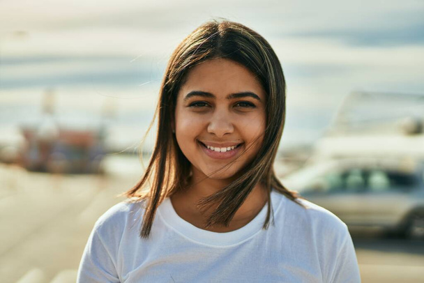 Молода латинська дівчина посміхається щаслива стоячи в місті
. - Фото, зображення