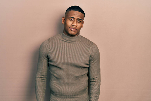 Young black man wearing casual turtleneck sweater relaxed with serious expression on face. simple and natural looking at the camera.  - Foto, Imagen