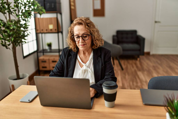 Mediana edad mujer de negocios caucásica utilizando el ordenador portátil de trabajo en la oficina. - Foto, Imagen