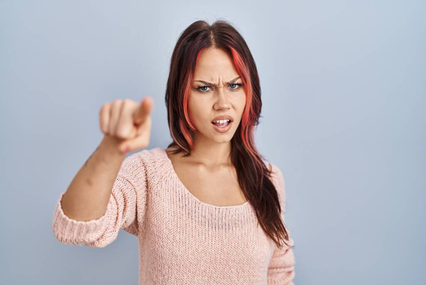 Mladá běloška v růžovém svetru na izolovaném pozadí ukazuje nespokojeně a frustrovaně na kameru, naštvaná a rozzuřená na vás  - Fotografie, Obrázek