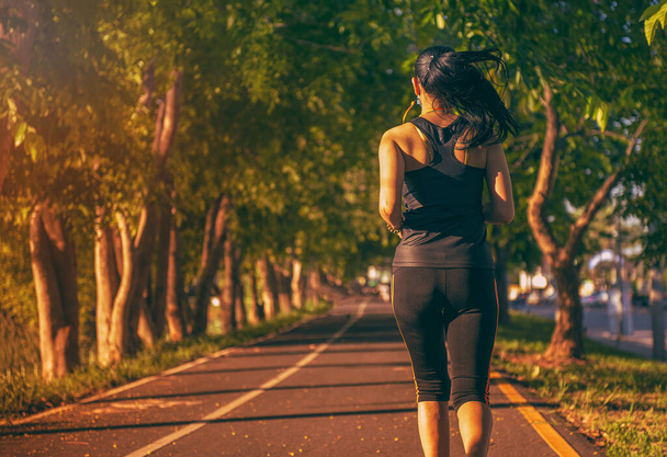 Женщина бегает в парке. Здоровый образ жизни и спортивные концепции. - Фото, изображение