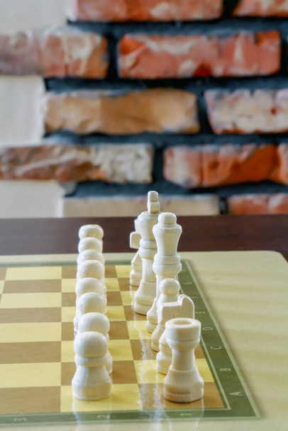 Masadaki satranç tahtasında duran beyaz satranç taşları. - Fotoğraf, Görsel