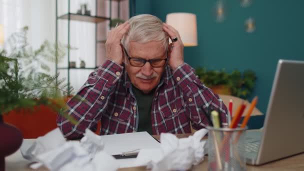 Älterer Mann arbeitet am Laptop, macht Notizen auf einem Blatt Papier, verärgert über schlechte Ergebnisse - Filmmaterial, Video