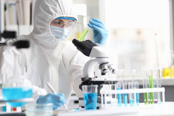 Вчений в захисному костюмі вивчає токсичні отруйні рідини в лабораторії
 - Фото, зображення