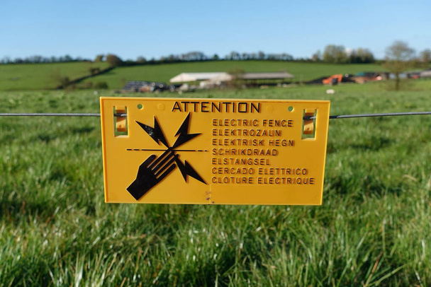Άποψη μιας γενικής πινακίδας στην αγροτική γη που διαβάζει "Προσοχή ηλεκτρικό φράχτη" - οι γλώσσες εκτός από τα αγγλικά στην πινακίδα όλα μεταφράζονται ως "ηλεκτρικό φράχτη" - Φωτογραφία, εικόνα