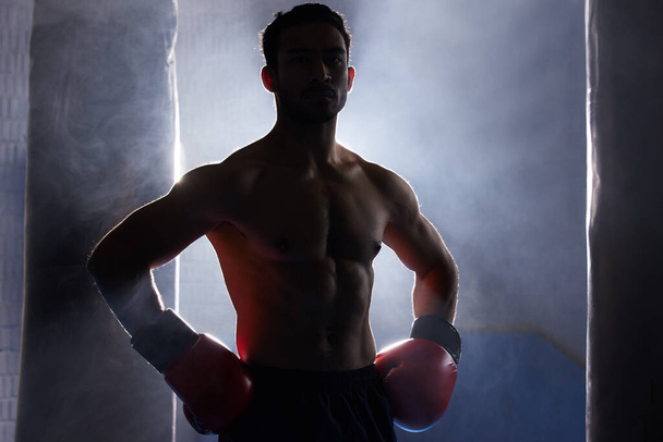Taistelen valmiina. Rajattu muotokuva siluetti nuori mies nyrkkeilijä seisoo kädet lantiolla harjoituksen jälkeen lävistys. - Valokuva, kuva
