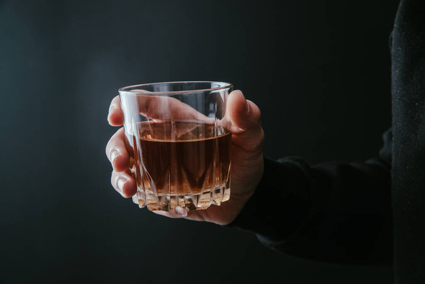 człowiek trzymający szklankę alkoholu na ciemnym tle - Zdjęcie, obraz