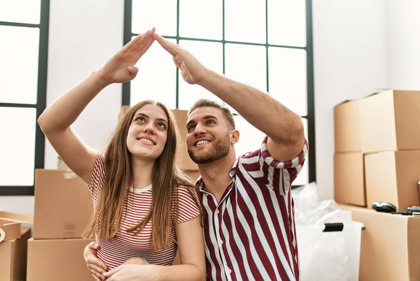 Mladý kavkazský pár dělá domácí symbol s rukama zdviženýma v novém domově. - Fotografie, Obrázek