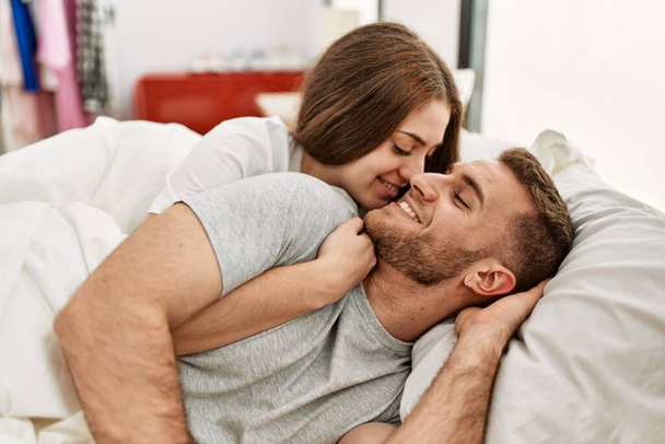 Jovem casal caucasiano sorrindo abraço feliz na cama em casa. - Foto, Imagem