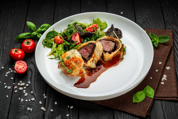 Rindfleisch Wellington, klassisches Steak, klassisches Rezept mit grünem Salat. Servieren von Essen in einem Restaurant. Gesundes Essen. Foto für die Speisekarte - Foto, Bild