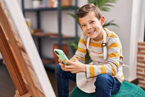 Blond child using smartphone drawing at art studio - Фото, изображение