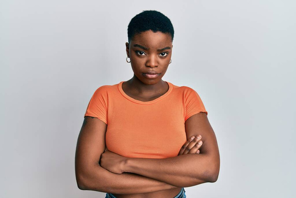 Giovane donna afroamericana che indossa casual t shirt arancione scettico e nervoso, espressione di disapprovazione sul viso con le braccia incrociate. persona negativa.  - Foto, immagini