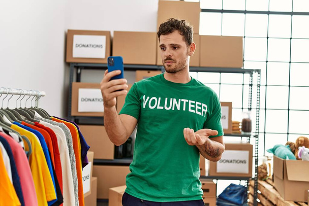 Fiatal spanyol férfi önkéntes egyenruhát visel videóhívással jótékonysági központban. - Fotó, kép