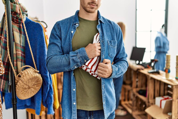 Молодой латиноамериканец ворует рубашку в магазине одежды. - Фото, изображение
