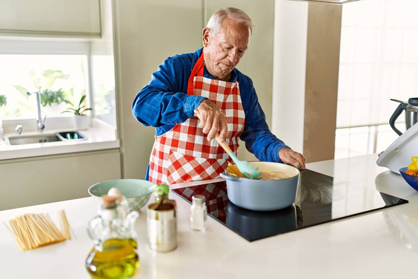 Senior man cooking spaghetti at kitchen - 写真・画像