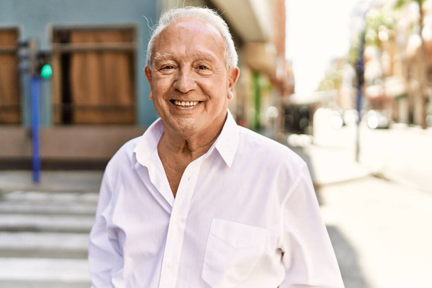 Ein älterer Mann mit grauen Haaren steht an einem sonnigen Tag glücklich im Freien. Glücklich lächelnd mit 70 in den Ruhestand. - Foto, Bild